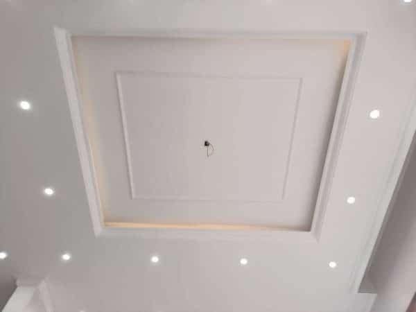 Trần thạch cao màu trắng với thiết kế hình vuông tinh tế và hệ thống đèn LED âm trần hiện đại, tạo không gian sáng sủa.