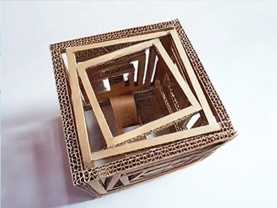 Mô hình kiến trúc sáng tạo từ giấy bìa cứng, góc chụp từ trên xuống, thể hiện cấu trúc hình học độc đáo và nghệ thuật tái chế.