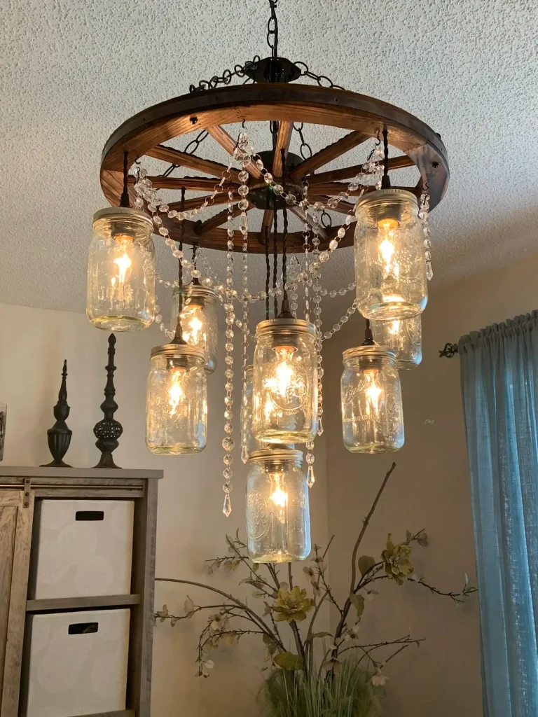 Đèn chùm phong cách rustic với lọ thủy tinh, bánh xe gỗ treo trên trần phòng khách, tạo ánh sáng ấm áp.