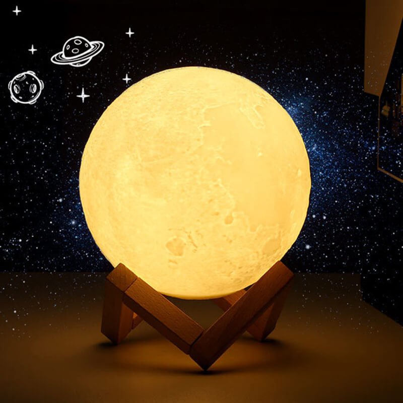Đèn mặt trăng 3D phát sáng màu vàng trên giá đỡ gỗ, nền là vũ trụ và các hành tinh vẽ tay.