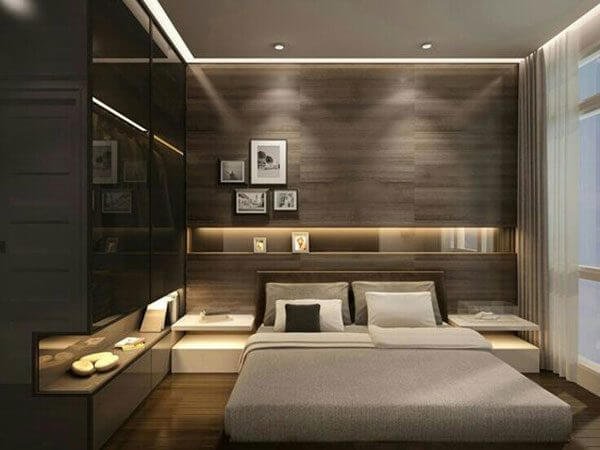 Phòng ngủ hiện đại với giường lớn, đèn LED âm trần, tường gỗ và tranh treo tạo không gian ấm áp và sang trọng.