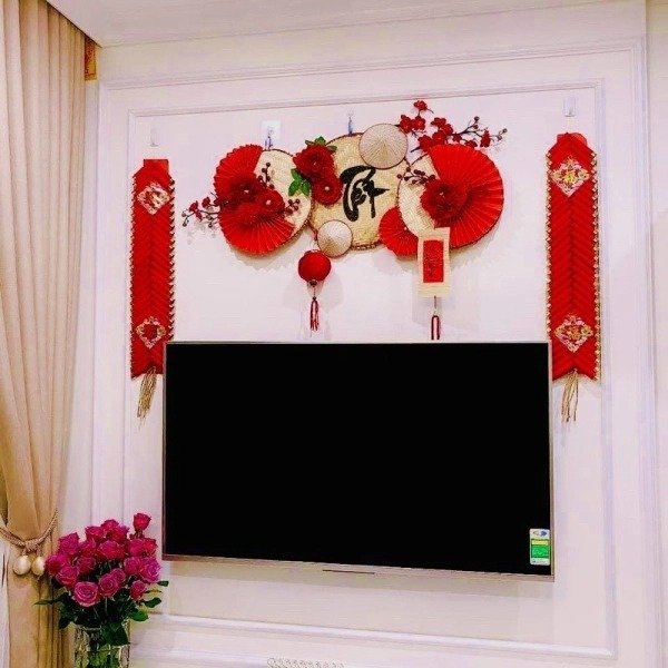 Trang trí phòng khách ngày Tết với hoa văn đỏ, bức tranh và hoa treo trên tường phòng khách tạo không khí ấm áp, tràn ngập sắc xuân.
